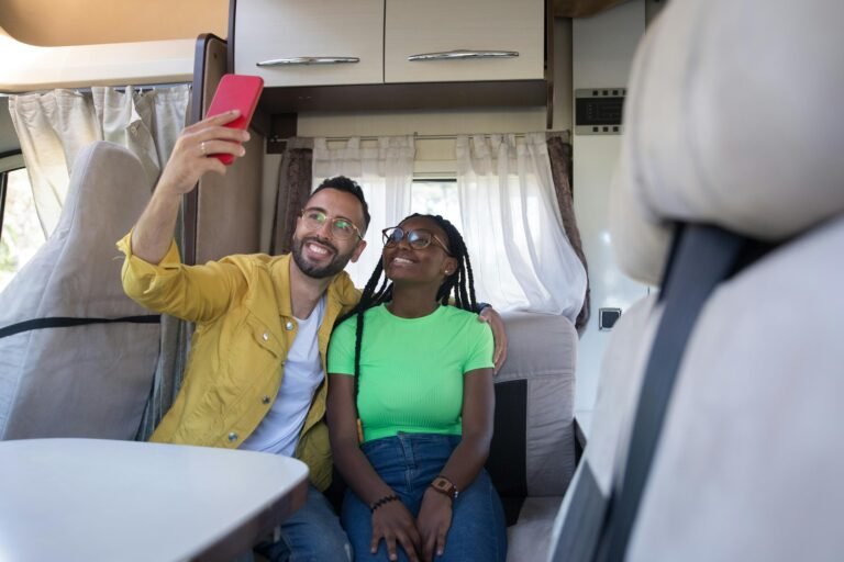 Happy couple taking a selfie inside a cozy camper van, smiling and enjoying their travel adventure.