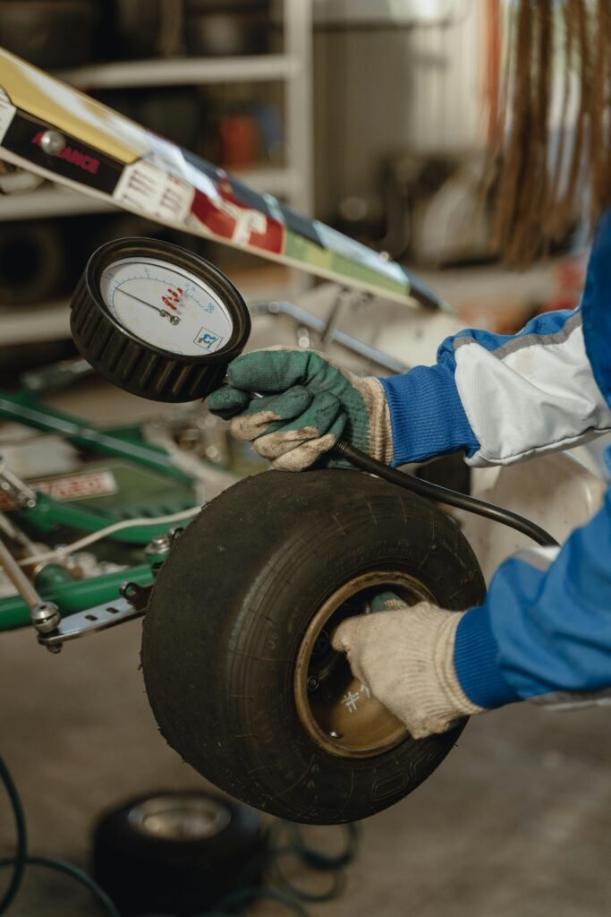 Close-up of a mechanic checking tire pressure on a go-kart in a garage workshop.
