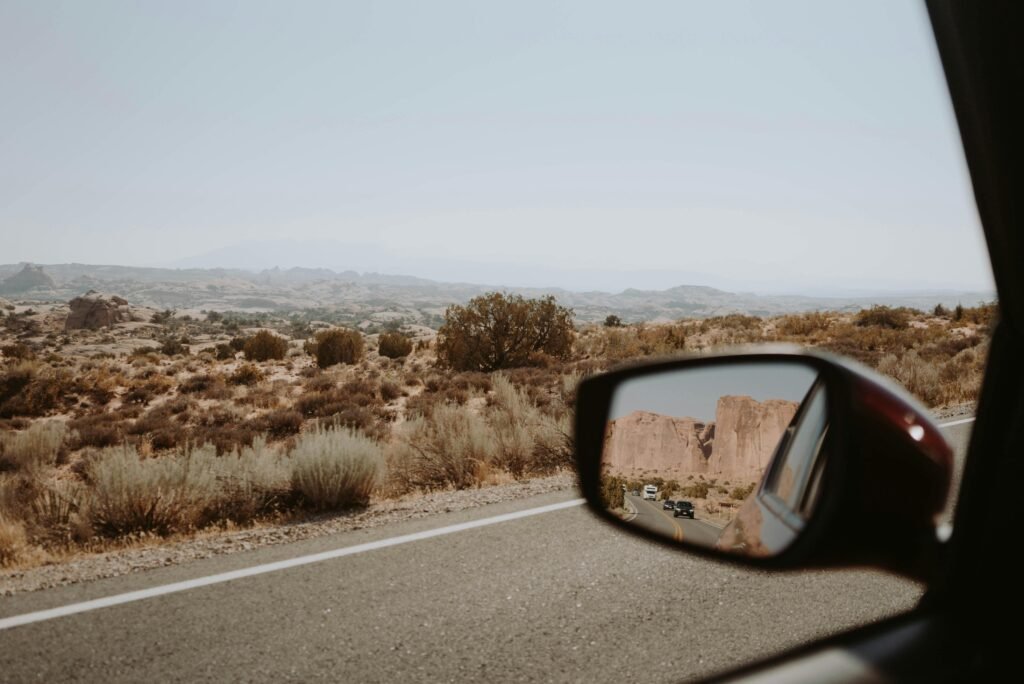 Capture of a scenic desert landscape during a road trip, viewed through a car's mirror.