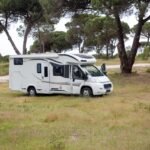Captivating shot of a campervan amidst a serene field in Portugal, surrounded by trees. Wassertank Wohnmobil