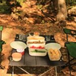 Inviting outdoor picnic scene with chairs, snacks, and natural greenery.