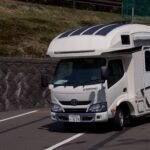 A sleek, white camper van parked on a sunny roadside, ready for adventure.