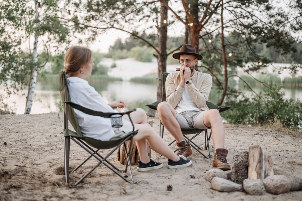 Relaxing outdoor scene with a couple near a campfire by the lake, playing harmonica.