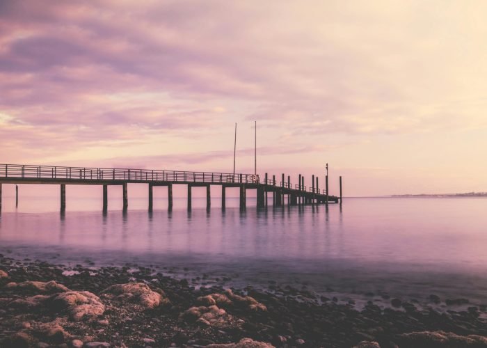 pexels-photo-168803-168803-1 A tranquil sunset over a pier in Konstanz, Germany with soft pink hues reflecting on the water.