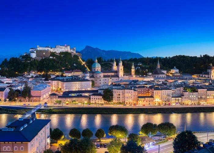 A breathtaking view of Salzburg cityscape with the illuminated Hohensalzburg Fortress at dusk. A breathtaking view of Salzburg cityscape with the illuminated Hohensalzburg Fortress at dusk.