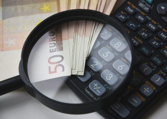 Euro bills under magnifying glass with calculator, symbolizing finance and analysis. Euro bills under magnifying glass with calculator, symbolizing finance and analysis.