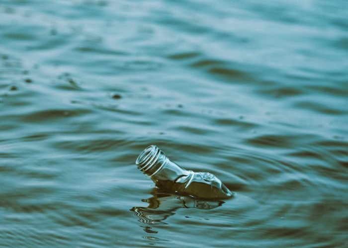 pexels-photo-27021830-27021830 A glass bottle floats in water creating ripples, illustrating pollution and environmental impact.