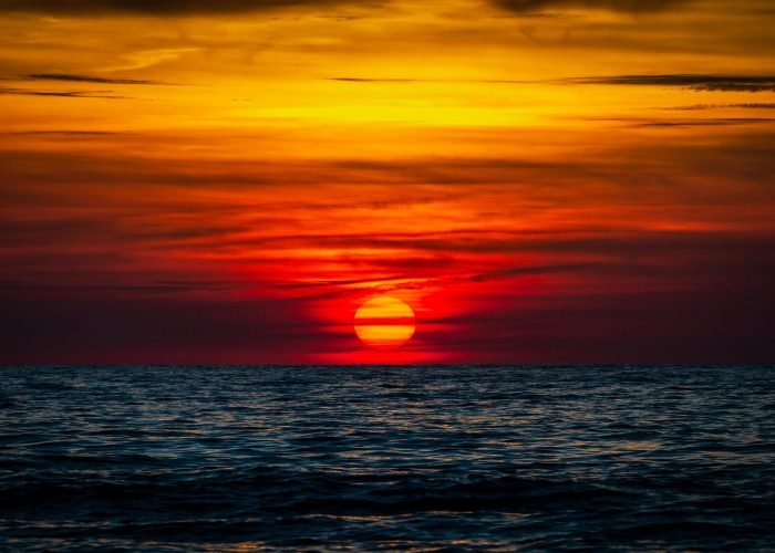 Stunning sunset over the ocean at Insel Hiddensee, featuring vibrant orange and red hues.