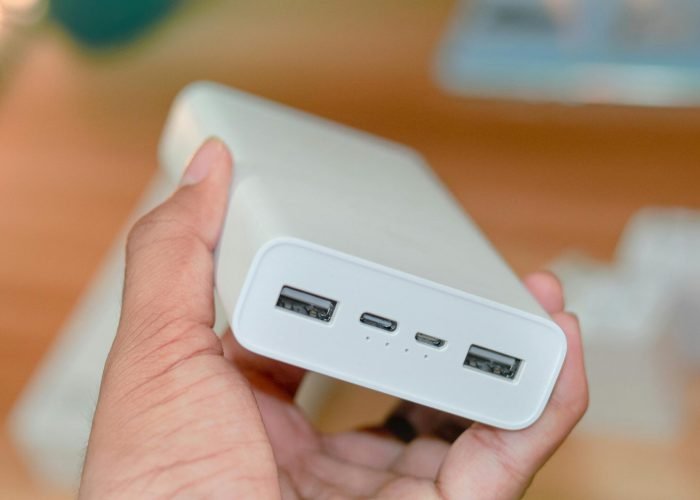 pexels-photo-4812315-4812315 Hand holding a powerbank showcasing its USB ports on a wooden background.